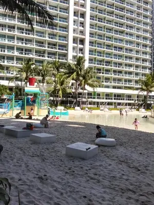 a group of people on a beach with a large building at OasisStaycation in Manila