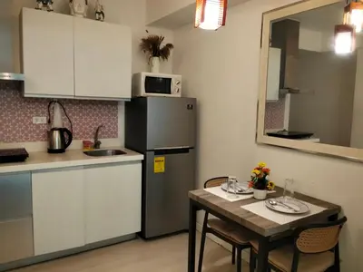 a small kitchen with a table and a refrigerator at OasisStaycation in Manila