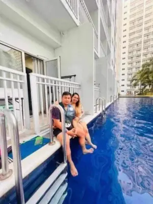 a man and woman sitting on the steps of a swimming pool at Wowstaycation in Manila