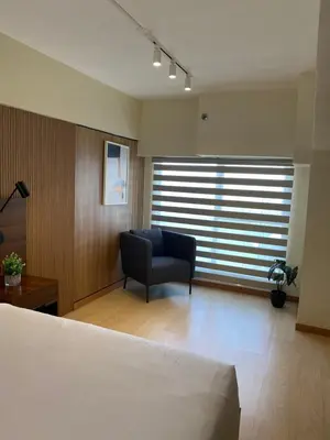 a bedroom with a bed and a chair and a window at EDSA Heights Unit 3422 Two br Penthouse Loft Unit AMA Tower residences in Manila