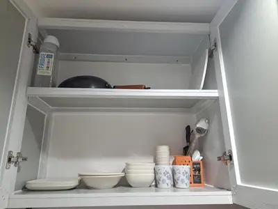 a white cabinet with plates and bowls in it at Ivy's CozyStaycation in Dasmariñas
