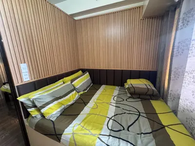 a small bedroom with a bed with yellow and gray pillows at Air Residences MKT in Manila
