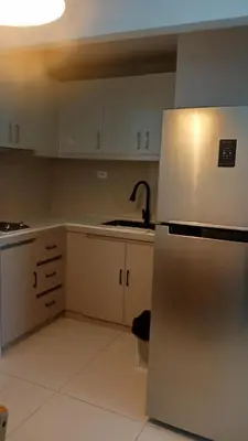 a kitchen with white cabinets and a stainless steel refrigerator at Charming 1BR with Natural Light in Manila