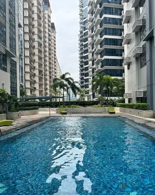 a swimming pool in the middle of two tall buildings at Elivion Staycations in McKinley Hill BGC with Pool near Venice Mall in Manila
