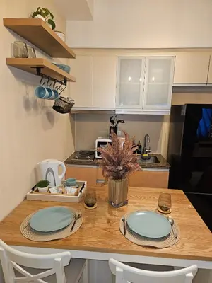 a kitchen with a wooden table with plates on it at Elivion Staycations in McKinley Hill BGC with Pool near Venice Mall in Manila