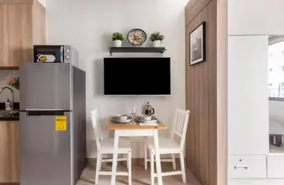 a kitchen with a table with chairs and a refrigerator at MOA Condotel 1BR fast WiFi in Manila