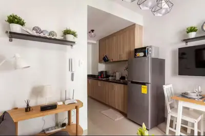 a kitchen with a stainless steel refrigerator and a table at MOA Condotel 1BR fast WiFi in Manila