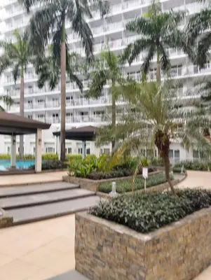 a large building with palm trees in front of it at Shell Residences Mall of Asia by Jade in Manila