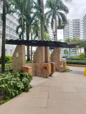 a circular bench in a park with palm trees at Shell Residences Mall of Asia by Jade in Manila