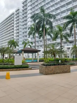 a large building with palm trees in front of it at Shell Residences Mall of Asia by Jade in Manila