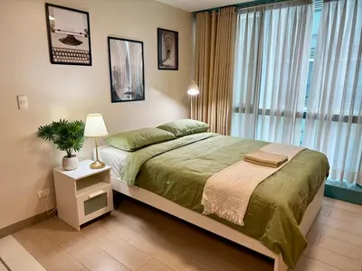 a bedroom with a large bed and a window at The Vibe BGC Uptown Apartment in Manila