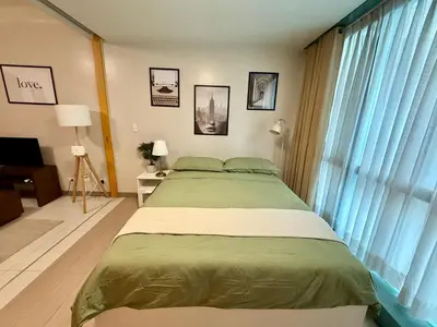 a bedroom with a bed and a large window at The Vibe BGC Uptown Apartment in Manila