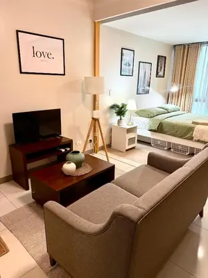 a living room with a couch and a bed at The Vibe BGC Uptown Apartment in Manila