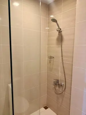 a shower with a glass door in a bathroom at The Vibe BGC Uptown Apartment in Manila