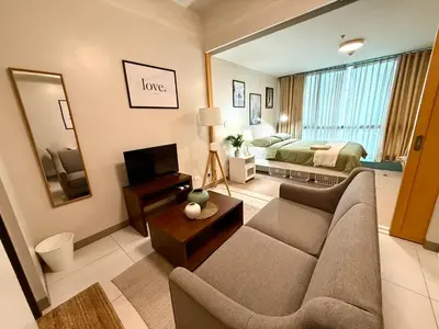 a living room with a couch and a bed at The Vibe BGC Uptown Apartment in Manila