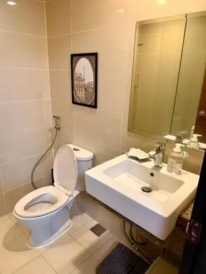 a bathroom with a white toilet and a sink at The Vibe BGC Uptown Apartment in Manila