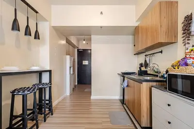 a kitchen with wooden cabinets and bar stools at Studio Lune - Heart of Makati in Manila