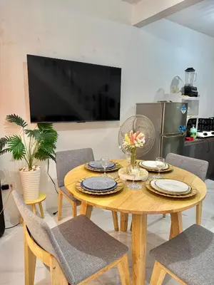a dining room with a table with chairs and a television at Sofias Townhouse for Rent in Dasmariñas