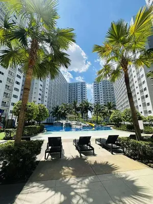 a pool with chairs and palm trees in a city at Shore Residences in Manila