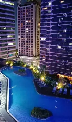 a view of a pool at night with tall buildings at Maison de Joie' in Manila