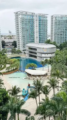 a resort with a pool and palm trees and buildings at Bahamas tower 1604 in Manila