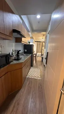 a kitchen with wooden cabinets and a counter top at The Framehaus with Free Parking at Sonora Garden Residences, Las Pinas in Manila