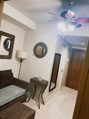 a living room with a couch and a table with a mirror at Pasay Moa Stay at Shell Residences in Manila