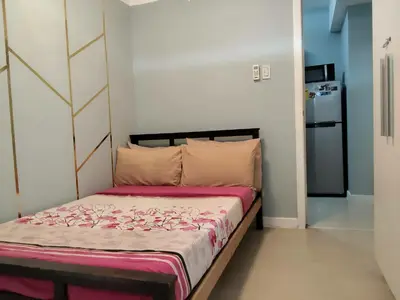 a bedroom with a bed with pink sheets and a refrigerator at Beach Bliss Your 2 BR Condo Retreat Awaits in Manila