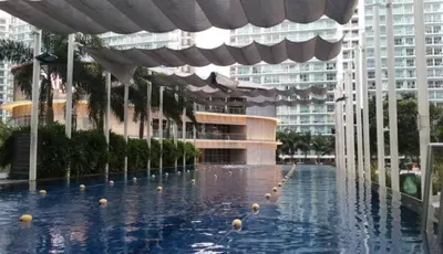 a swimming pool in a building with an umbrella at Beach Bliss Your 2 BR Condo Retreat Awaits in Manila