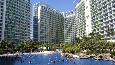 a group of people in a swimming pool in front of two tall buildings at Beach Bliss Your 2 BR Condo Retreat Awaits in Manila
