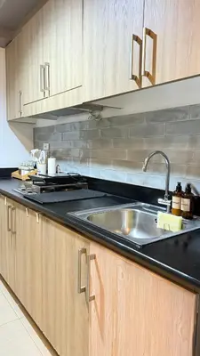 a kitchen with a sink and wooden cabinets at The Luxe Nook Shore Residences MOA in Manila