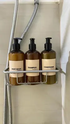 three bottles of soap on a shelf in a bathroom at The Luxe Nook Shore Residences MOA in Manila