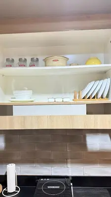 a shelf with bowls and utensils in a kitchen at The Luxe Nook Shore Residences MOA in Manila