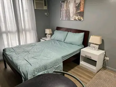 a bedroom with a bed with a green comforter at Vacation in Tribecca Towers in Manila