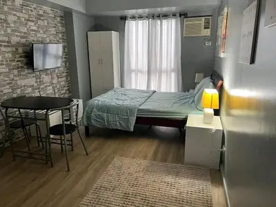 a small bedroom with a bed and a table at Vacation in Tribecca Towers in Manila