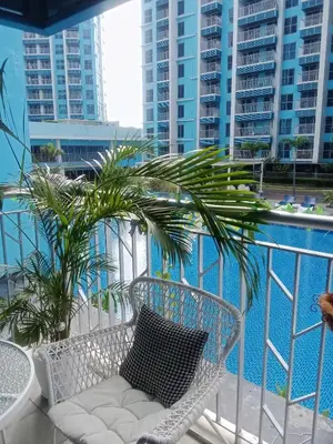 a white chair sitting on a balcony with a palm tree at Cozy Retreat 3 BR unit The Bayshore in Manila