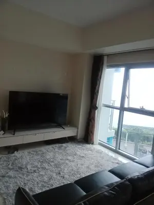 a living room with a flat screen tv and a couch at Cozy Retreat 3 BR unit The Bayshore in Manila