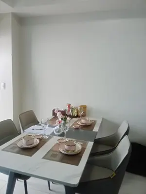 a dining room table with chairs and a white table with glasses at Cozy Retreat 3 BR unit The Bayshore in Manila