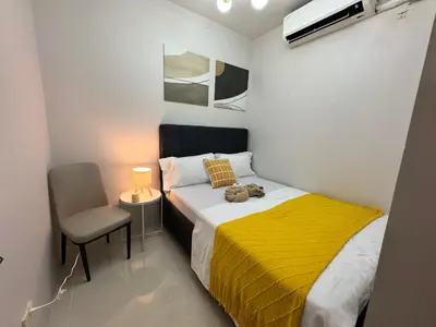 a small bedroom with a bed with a yellow blanket at S Residences Family Room 512 by Prime Stay MOA in Manila