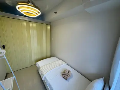 a small room with a bed and a light at S Residences Family Room 512 by Prime Stay MOA in Manila