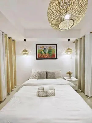 a bedroom with a large white bed and a large chandelier at Hotel Essence Service Road in Manila