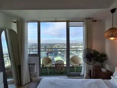 a bedroom with a large window with a table and chairs at Hotel Essence Service Road in Manila
