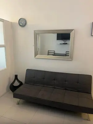 a couch in a living room with a mirror at Hotel Essence Service Road in Manila