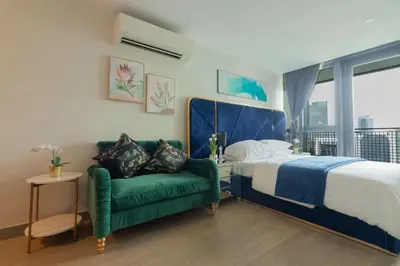 a bedroom with a bed and a green couch at Century Spire Condominium, Makati City in Manila