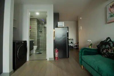 a living room with a green couch and a refrigerator at Century Spire Condominium, Makati City in Manila