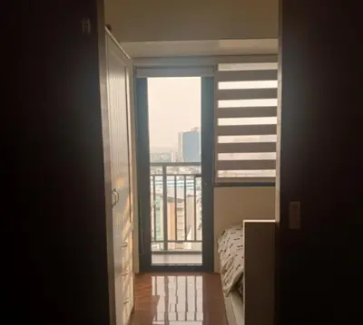 a room with a bed and a view of a balcony at air residences in Manila