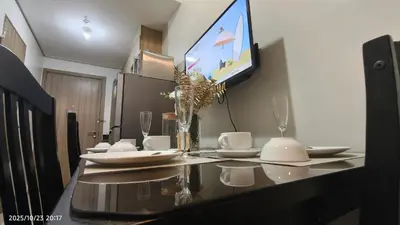 a dining room table with a television on the wall at Shore Residences Pasay in Manila