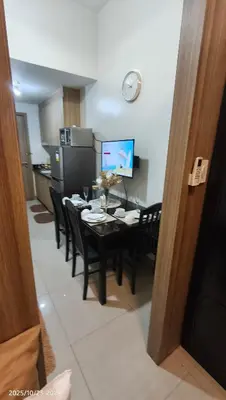 a kitchen with a dining room table with black chairs at Shore Residences Pasay in Manila