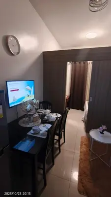 a living room with a table with chairs and a television at Shore Residences Pasay in Manila