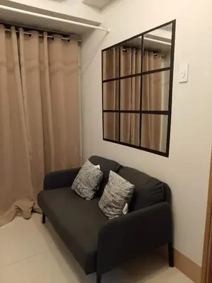 a black couch in a room with a mirror at Pasay FL Staycation in Manila